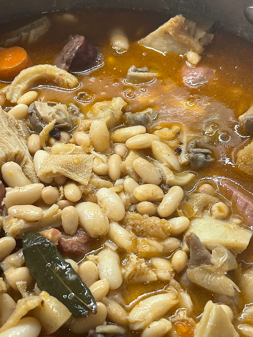 O tacho com o feijão branco a ser adicionado ao molho, com pedaços de cenoura e enchido visíveis