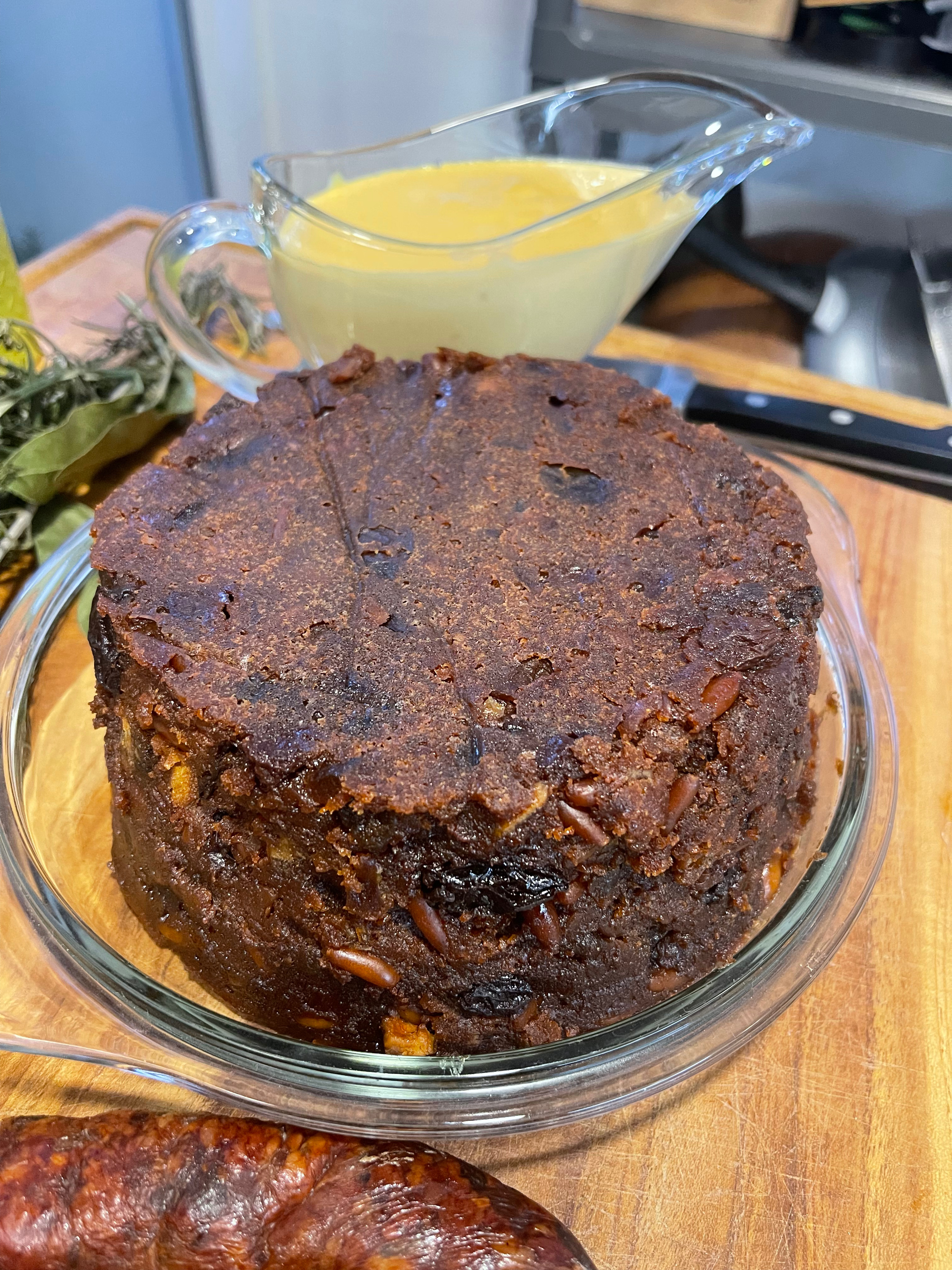 O bolo desenformado num prato de vidro, com um molheiro de custarda amarela ao fundo